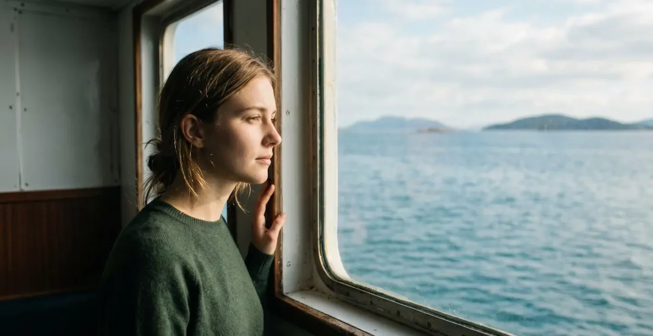 Personne contemplant l'horizon marin depuis une cabine de ferry avec lumière naturelle douce