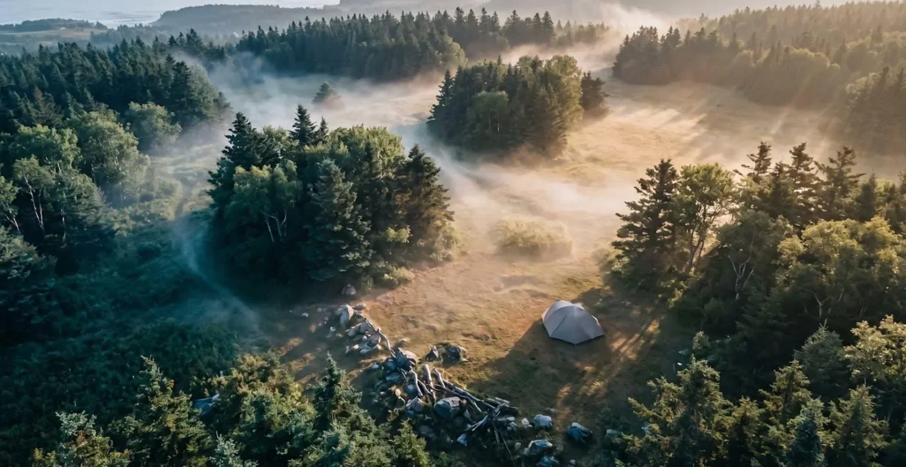 Vue aérienne montrant l'orientation stratégique d'une tente de camping par rapport aux arbres et au vent